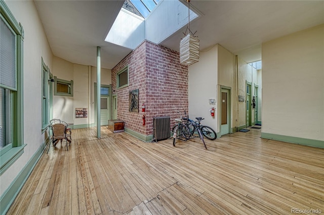 unfurnished living room with a skylight, light hardwood / wood-style floors, and a high ceiling