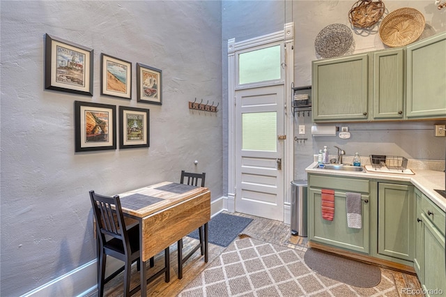 kitchen featuring a sink, light countertops, light wood-type flooring, and green cabinetry