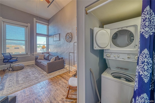 washroom with stacked washer and dryer, wood-type flooring, and ceiling fan