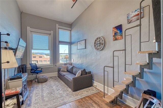 living area featuring a textured wall, baseboards, and wood finished floors
