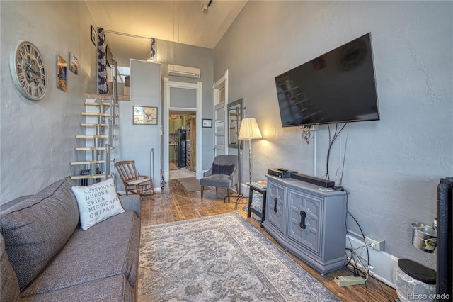 living room featuring wood finished floors, an AC wall unit, and lofted ceiling
