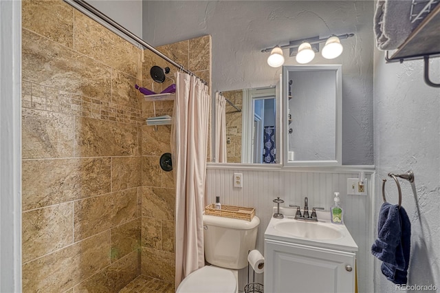 bathroom featuring a tile shower, vanity, and toilet