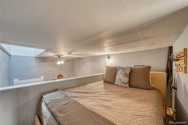bedroom with a ceiling fan and a textured wall