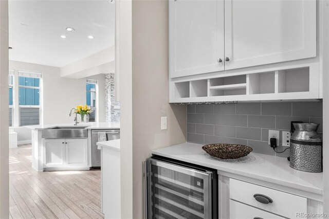 bar featuring white cabinetry, beverage cooler, and sink