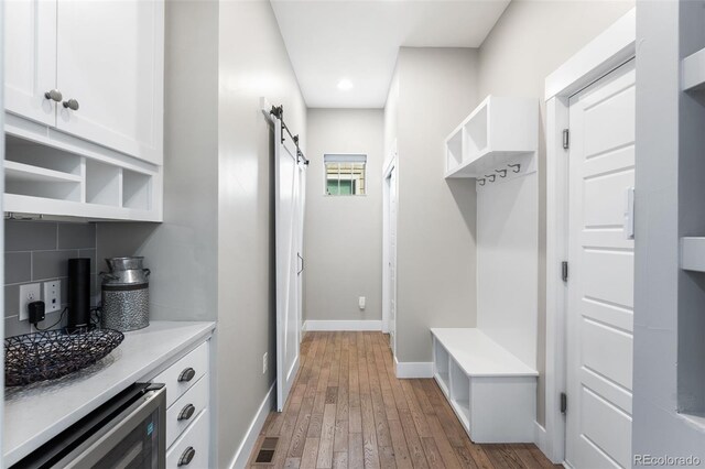 mudroom featuring a barn door, wood-type flooring, and wine cooler