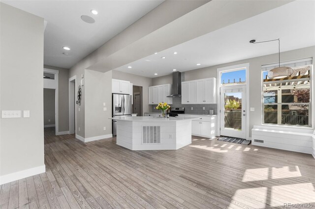 kitchen with white cabinets, a kitchen island with sink, wall chimney exhaust hood, and stainless steel appliances