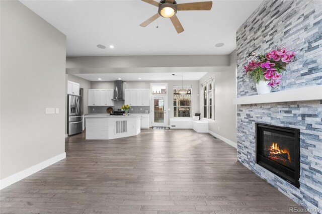 unfurnished living room featuring dark hardwood / wood-style flooring, a fireplace, and ceiling fan with notable chandelier