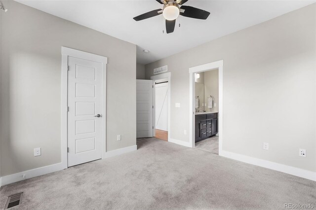 unfurnished bedroom with ceiling fan, light colored carpet, and connected bathroom