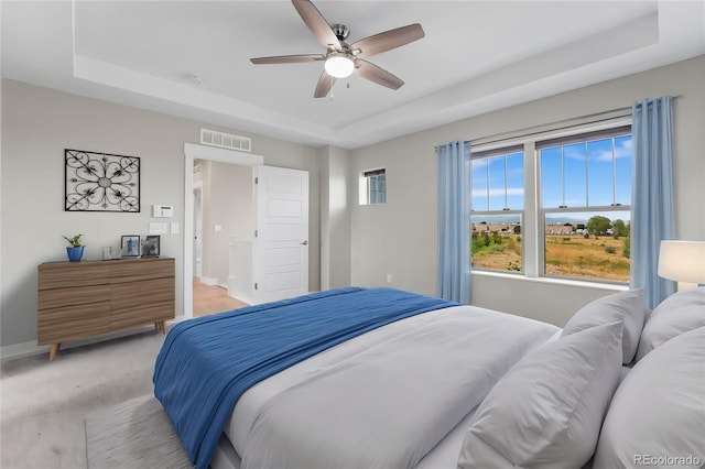 bedroom with carpet flooring, a tray ceiling, and ceiling fan