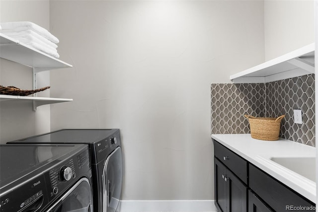 clothes washing area with cabinets and washer and dryer