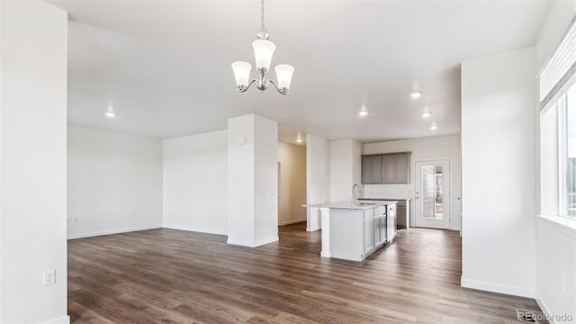 unfurnished living room with a notable chandelier, sink, and dark hardwood / wood-style floors