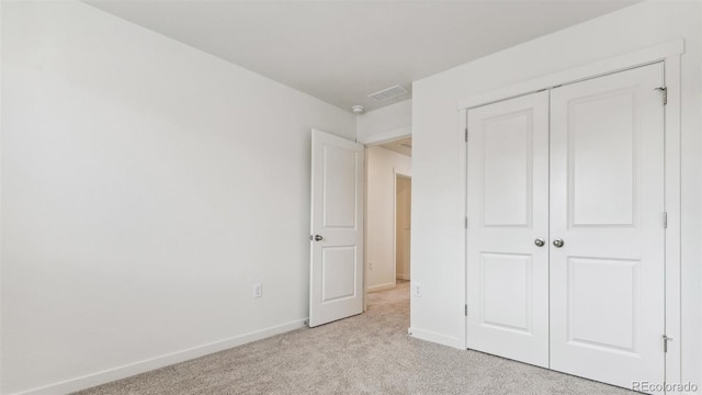 unfurnished bedroom featuring a closet and light colored carpet