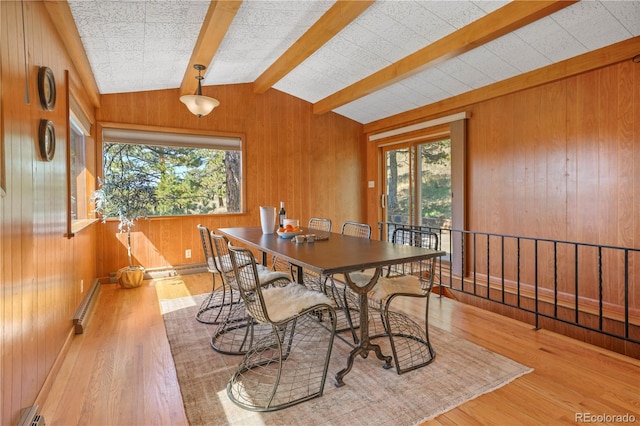 dining space featuring hardwood / wood-style flooring, lofted ceiling with beams, wooden walls, and a baseboard radiator