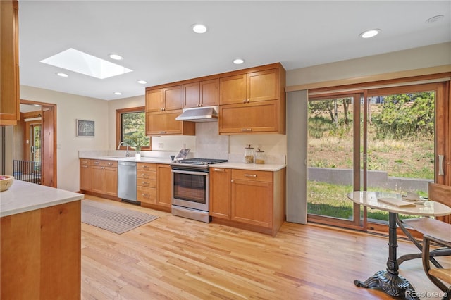 kitchen featuring sink, light hardwood / wood-style flooring, appliances with stainless steel finishes, and a skylight