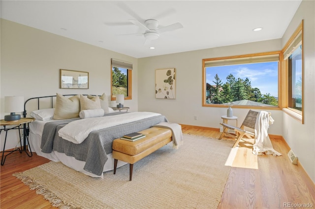 bedroom featuring light hardwood / wood-style floors, multiple windows, and ceiling fan