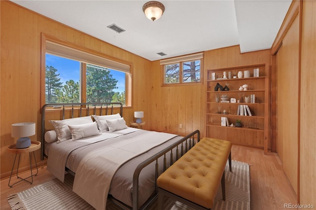 bedroom with light hardwood / wood-style floors and wood walls