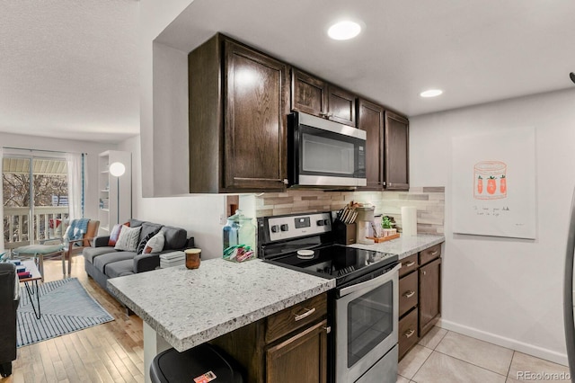 kitchen with dark brown cabinets, open floor plan, light countertops, backsplash, and stainless steel appliances