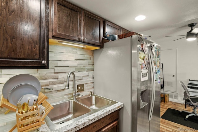 kitchen featuring decorative backsplash, dark brown cabinetry, ceiling fan, stainless steel fridge, and a sink