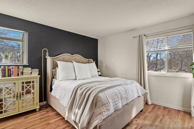 bedroom with a textured ceiling, wood finished floors, and multiple windows
