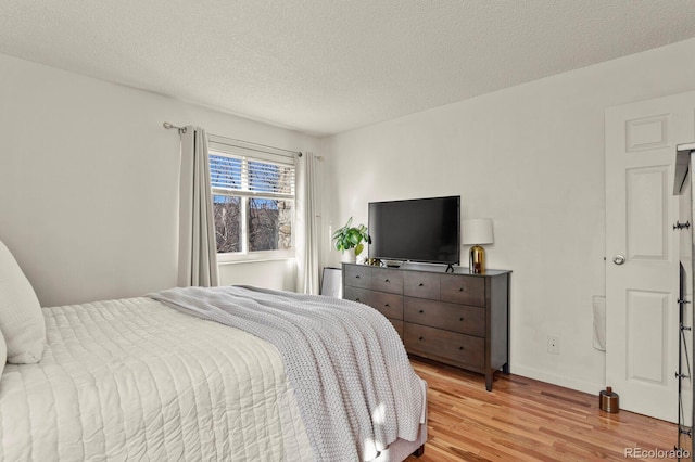 bedroom with light wood-type flooring and a textured ceiling