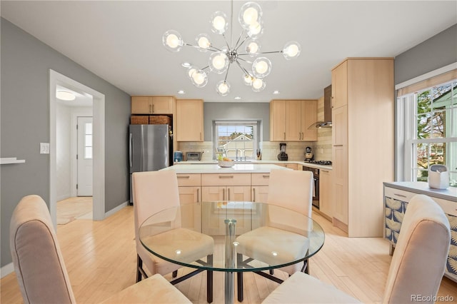 dining space with sink, a chandelier, and light hardwood / wood-style flooring