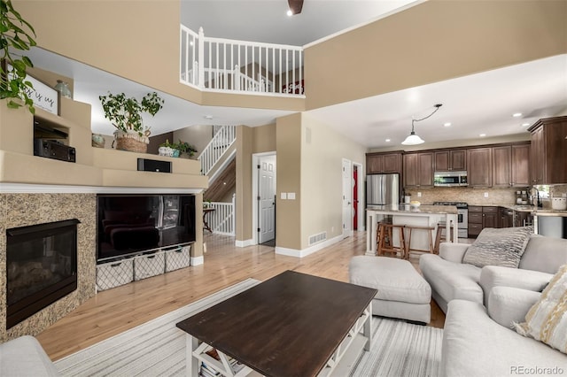 902 Jarvis Dr, Erie, CO 80516 - living room featuring light wood-style flooring, baseboards, a high ceiling, a glass covered fireplace, and recessed lighting