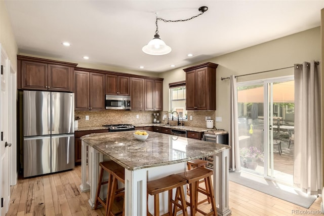 902 Jarvis Dr, Erie, CO 80516 - kitchen with appliances with stainless steel finishes, light wood-style floors, tasteful backsplash, a center island, and recessed lighting
