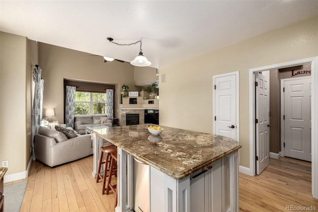 902 Jarvis Dr, Erie, CO 80516 - kitchen with light wood-type flooring, a glass covered fireplace, dark stone countertops, and open floor plan