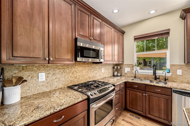 902 Jarvis Dr, Erie, CO 80516 - kitchen with stainless steel appliances, a sink, light stone counters, light wood finished floors, and recessed lighting
