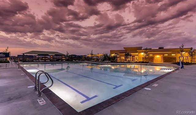 pool at dusk featuring a patio