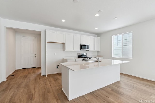 kitchen featuring a kitchen island with sink, light hardwood / wood-style flooring, white cabinets, and appliances with stainless steel finishes