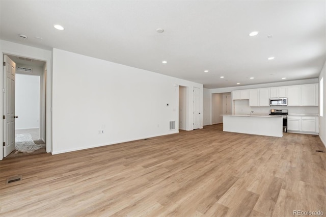 unfurnished living room featuring sink and light wood-type flooring