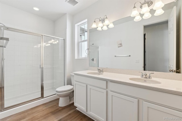 bathroom with vanity, a shower with door, hardwood / wood-style flooring, toilet, and a chandelier