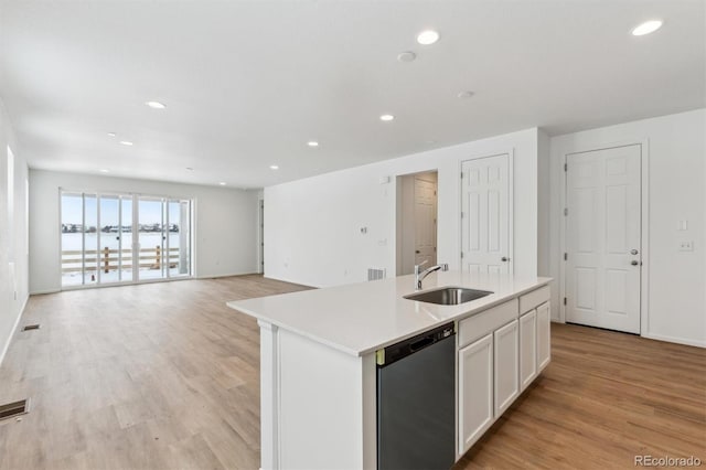 kitchen with light wood-type flooring, stainless steel dishwasher, sink, a center island with sink, and white cabinets