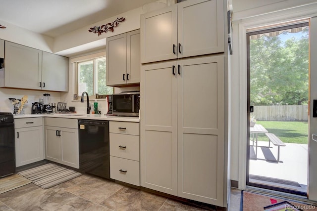 kitchen with black appliances, a sink, and light countertops