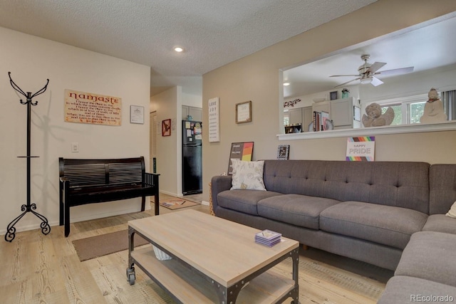 living room with light wood finished floors, ceiling fan, a textured ceiling, and recessed lighting