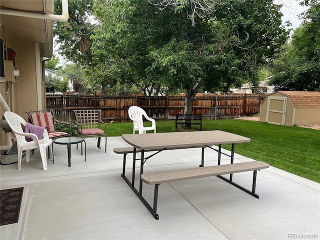 view of patio featuring outdoor dining space, a fenced backyard, a storage unit, and an outdoor structure