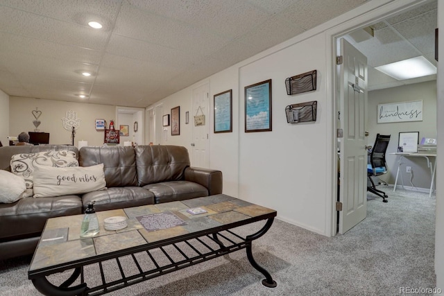 carpeted living room featuring a drop ceiling and baseboards