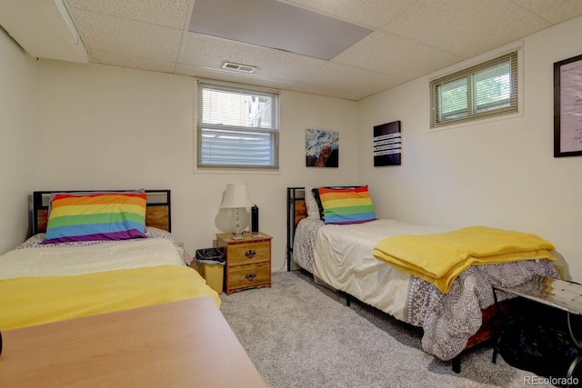 carpeted bedroom with visible vents and a drop ceiling