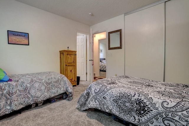 carpeted bedroom with a textured ceiling and a closet