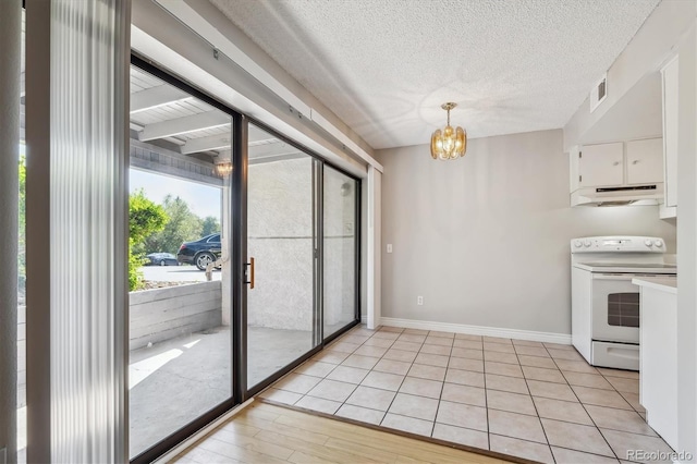 6490 S Dayton St Unit L02, Englewood, CO 80111 - kitchen with electric range, under cabinet range hood, white cabinets, a chandelier, and pendant lighting