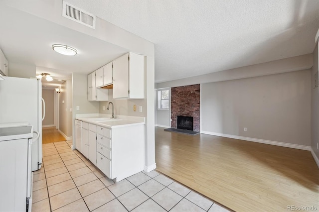 6490 S Dayton St Unit L02, Englewood, CO 80111 - kitchen featuring white range, light countertops, white cabinetry, light tile patterned flooring, and a brick fireplace