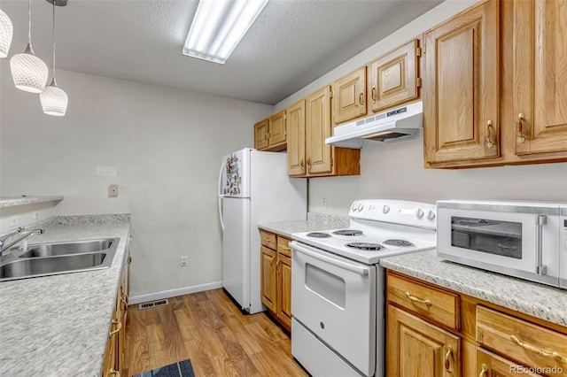 kitchen with light wood finished floors, light countertops, a sink, white appliances, and under cabinet range hood