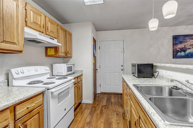 kitchen with white appliances, wood finished floors, light countertops, under cabinet range hood, and a sink