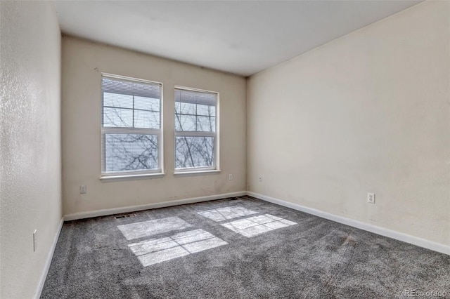 spare room featuring a textured wall, carpet floors, visible vents, and baseboards