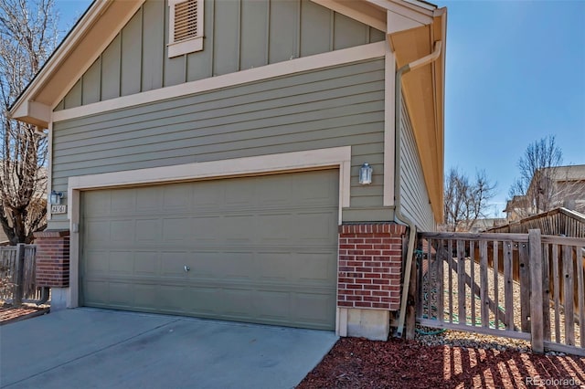 garage featuring concrete driveway and fence