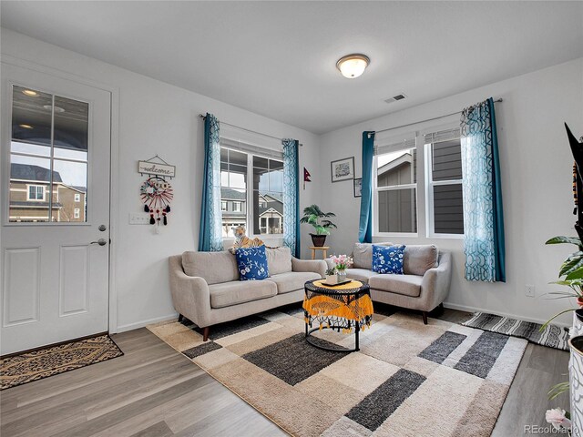 living area featuring visible vents, baseboards, and wood finished floors