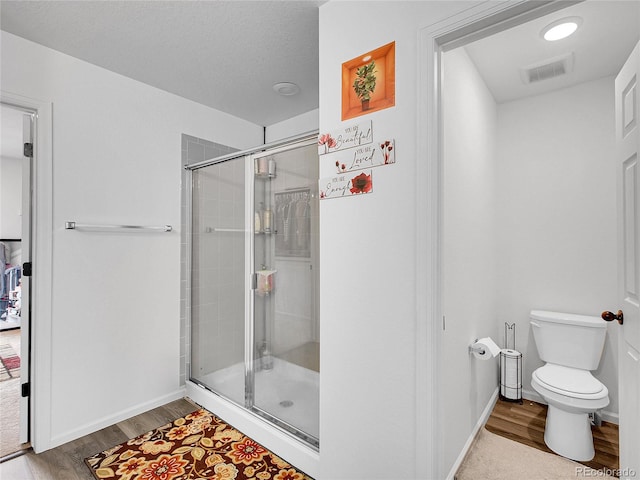 full bathroom featuring visible vents, wood finished floors, and a stall shower