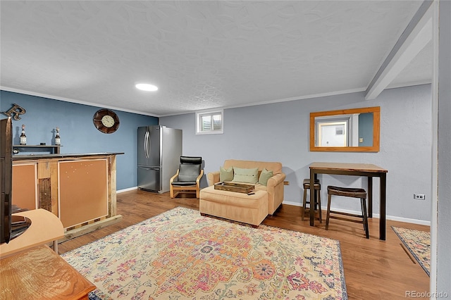 living room with crown molding, light wood-style flooring, baseboards, and a textured ceiling