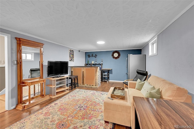 living room with wood finished floors, baseboards, and ornamental molding